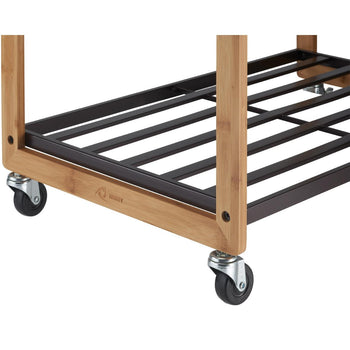 A close-up shot of the base of a Trinity 3-Bag Bamboo Laundry Cart, showing its bamboo frame, bronze metal shelves, and four caster wheels. The Trinity logo is visible on the bottom left bamboo support.