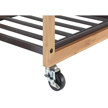 A close-up shot shows the bottom right corner of a Trinity 3-Bag Bamboo Laundry Cart. A dark bronze metal frame with horizontal bars supports a lighter bamboo frame, which rests on a single silver caster wheel with a black rubber wheel and a locking mechanism.