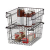 A close-up studio shot of two dark bronze wire baskets stacked on top of each other, containing jars and cans of food. The baskets are empty and isolated on a white background.