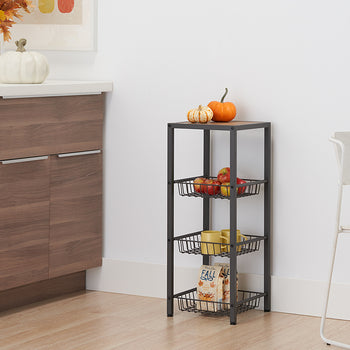 A dark gray metal shelving unit stands in a corner with a light wood top. It has three wire baskets holding apples, mugs, and a 