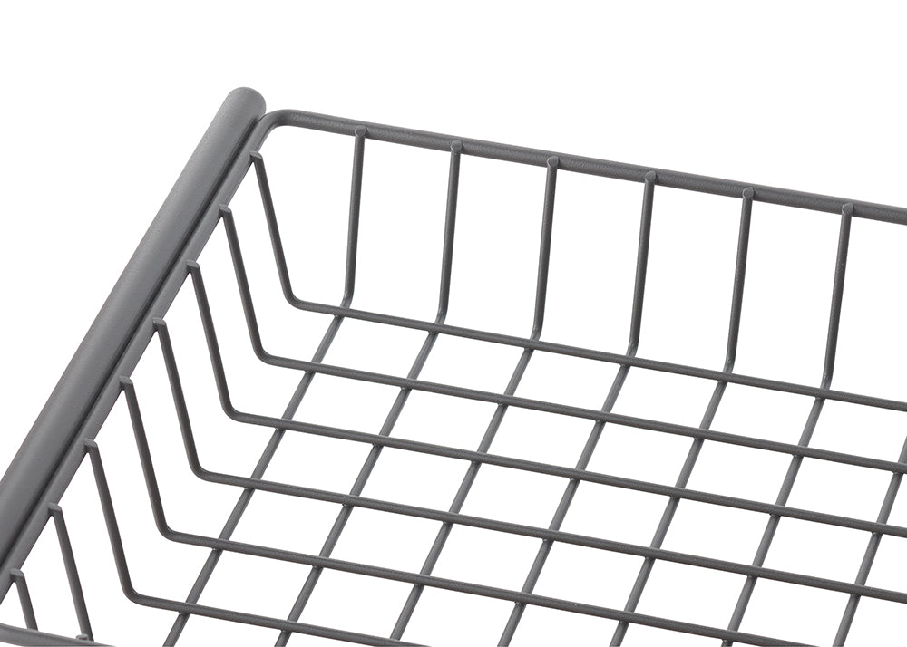 A close-up shot shows a gray, rectangular wire basket with a grid pattern at the bottom and vertical bars forming the sides. The smooth, rounded edge of the basket's rim is visible in the upper left corner.