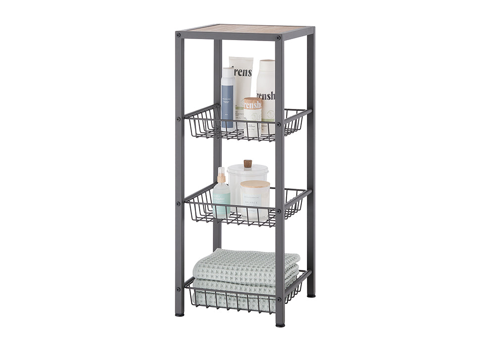 A dark gray metal shelving unit with three wire baskets and a wooden top shelf is displayed against a white background. The shelves hold various bathroom items including towels, lotions, sprays, and candles, suggesting its use for storage.