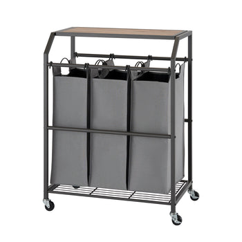 A laundry cart with three gray fabric bags hanging side-by-side from a metal frame with a wooden top. The cart has four wheels and a wire shelf at the bottom.