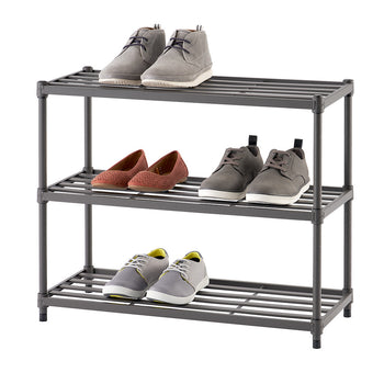 A three-tier metal shoe rack with a dark gray finish holds four pairs of shoes, including boots, dress shoes, casual sneakers, and flats. The shoes are neatly arranged on the shelves, showcasing a variety of styles and colors.