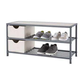 A three-tiered slate gray metal shoe bench with a light-colored top is shown against a white background. The middle and bottom shelves have horizontal slats and hold several pairs of shoes, while the top shelf also has two light-colored fabric storage baskets on the left side.