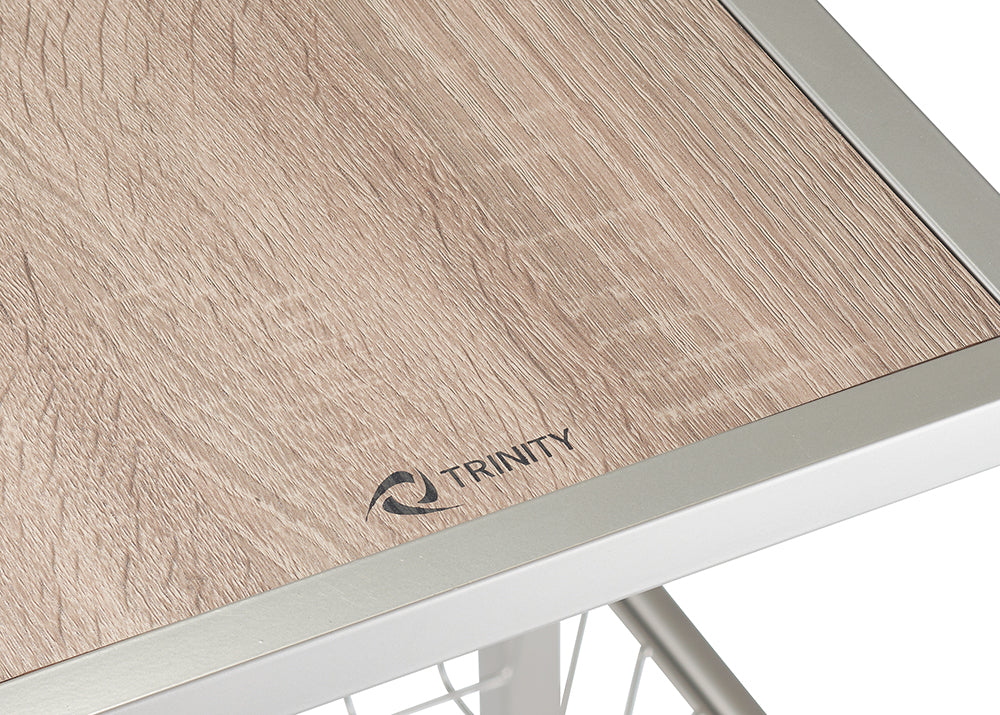 A close-up shot shows a light brown, wood-grain tabletop with a metallic silver frame. The word "TRINITY" is printed in black on the table top.