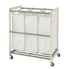 A white-colored Trinity 3-Bag Laundry Cart is shown with three removable white canvas laundry bags. The cart has a metal frame, a hanging bar for the bags, and wheels for portability.