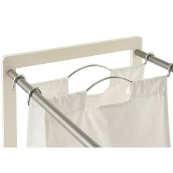 A close-up shot of a white laundry hamper with two of its three cloth bags visible. The bags are suspended by metal rods and hooks from a light-colored frame.