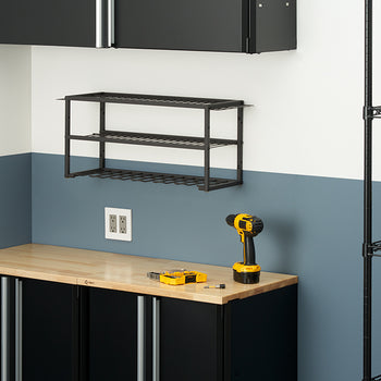 A black metal two-tier shelf with a built-in power tool rack is mounted on a two-toned wall. Below it, a black cabinet with a wooden workbench top holds a yellow and black power drill.