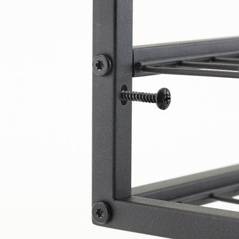A close-up shot shows a black metal frame with a loose screw sticking out of a hole. The screw is a black self-tapping screw with a Phillips head, and another screw of the same type is fully inserted into the frame above it.