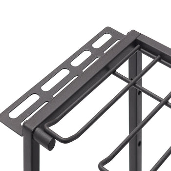 A close-up, eye-level shot shows the upper corner of a charcoal-gray metal wire rack. The rack features a perforated top shelf and a section below with thick parallel wires for storage.