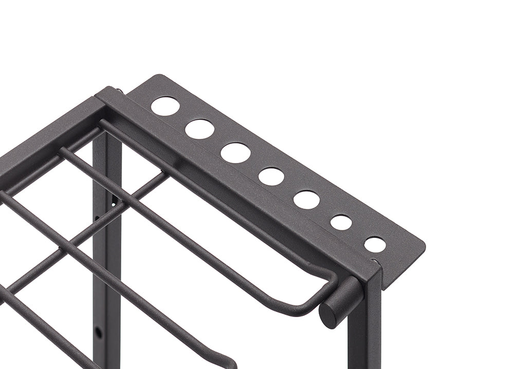 A close-up, high-angle shot of the top corner of a black metal wire storage rack. The rack has a gridded wire bottom and a perforated top shelf with different-sized holes, designed to hold various tools or utensils.