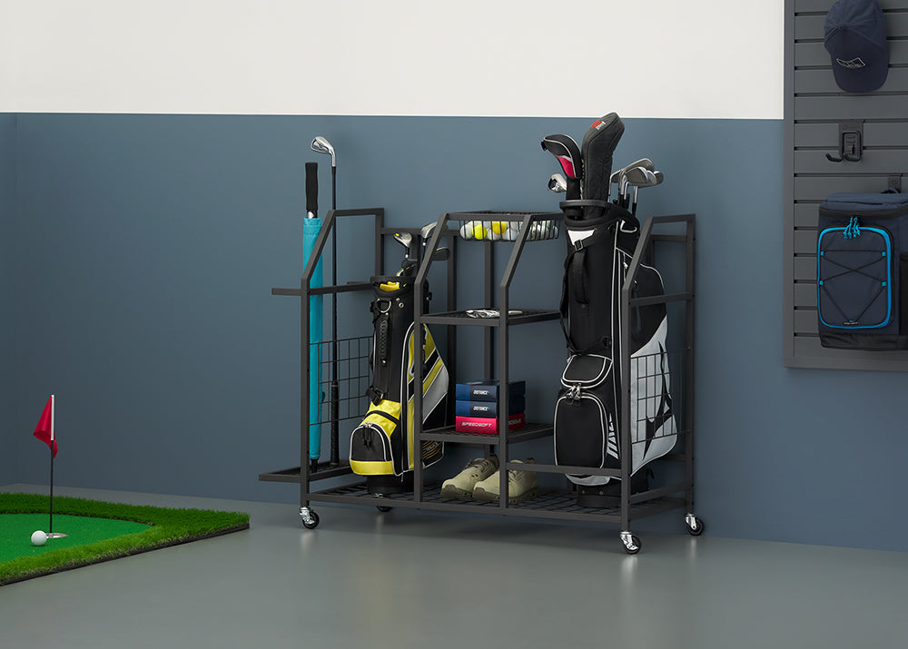 A black metal rolling storage cart holds golf equipment, including two bags, clubs, and shoes, against a grey wall. To the side, a putting green with a ball and flag is set up, complementing the scene of a organized personal golf garage or practice area.