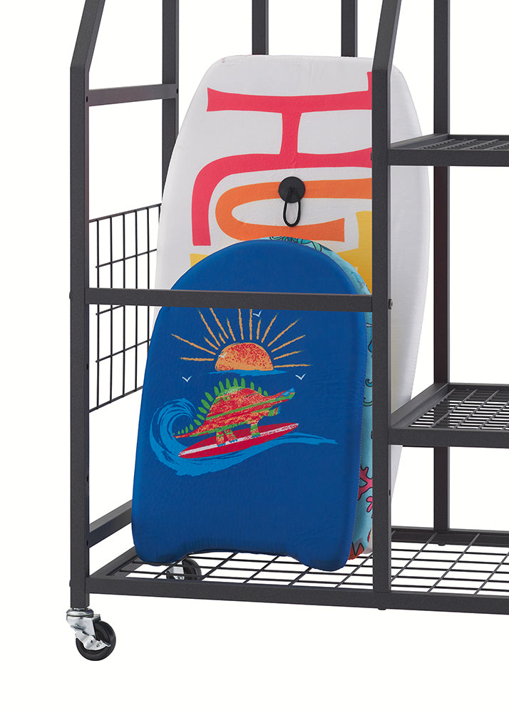 A close-up view of the base of a black rolling storage cart shows two bodyboards neatly organized on its bottom wire mesh shelf, against a clean white background. In front, a smaller blue bodyboard features a vibrant graphic of a dinosaur surfing at sunset, while a larger white board sits behind it, showcasing large colorful letters and a black handle.