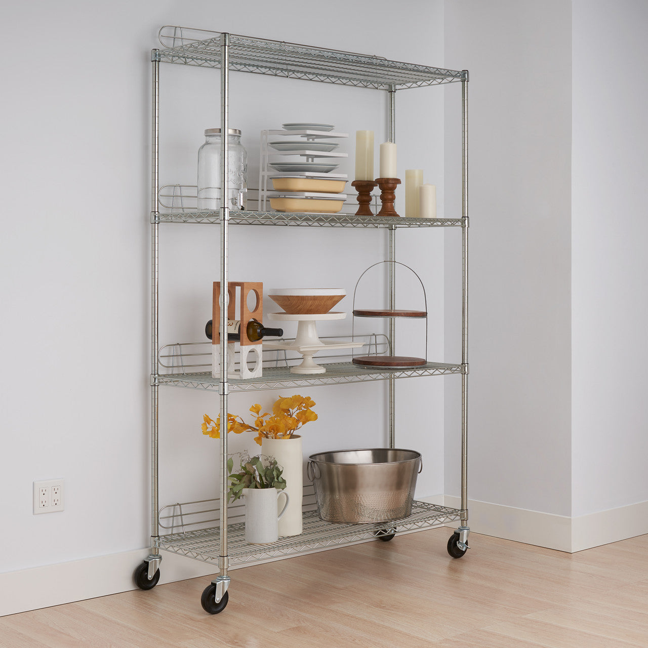 A 4-Tier Wire Shelving Rack with Wheels is shown, organized with various kitchen and home items. The shelves hold plates, dishes, candles, a wine bottle, decorative bowls, and a metal bucket, among other things.