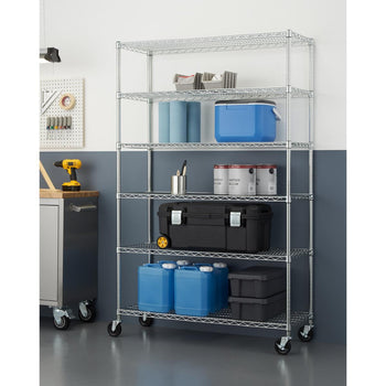 A chrome metal six tier wire shelving unit on wheels is organized with various storage items, including blue jugs, toolboxes, paint cans, paper towels, and a blue cooler. The unit is placed against a two-tone wall in a garage or workshop setting, next to a workbench with tools.