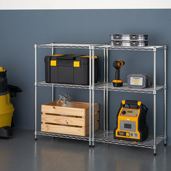 A silver metal wire shelving unit with three tiers holds various items, including a black and yellow toolbox, a wooden crate, and a yellow and black jump starter. A yellow wet/dry vacuum is on the left, and the shelving unit is against a dark blue wall.