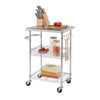 A stainless steel kitchen cart with two wire shelves and rolling wheels is shown on a white background. The top stainless steel surface holds a wooden knife block with knives, a wooden cutting board with tomatoes, and two glass jars with lids.