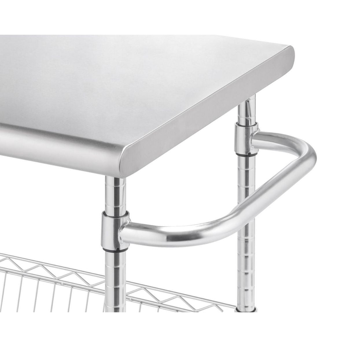 A close-up shot shows a portion of a stainless steel kitchen cart with a rounded edge countertop. Below the countertop, a curved stainless steel handle is attached to the chrome-finished support poles, and a glimpse of a wire shelf is visible at the bottom.