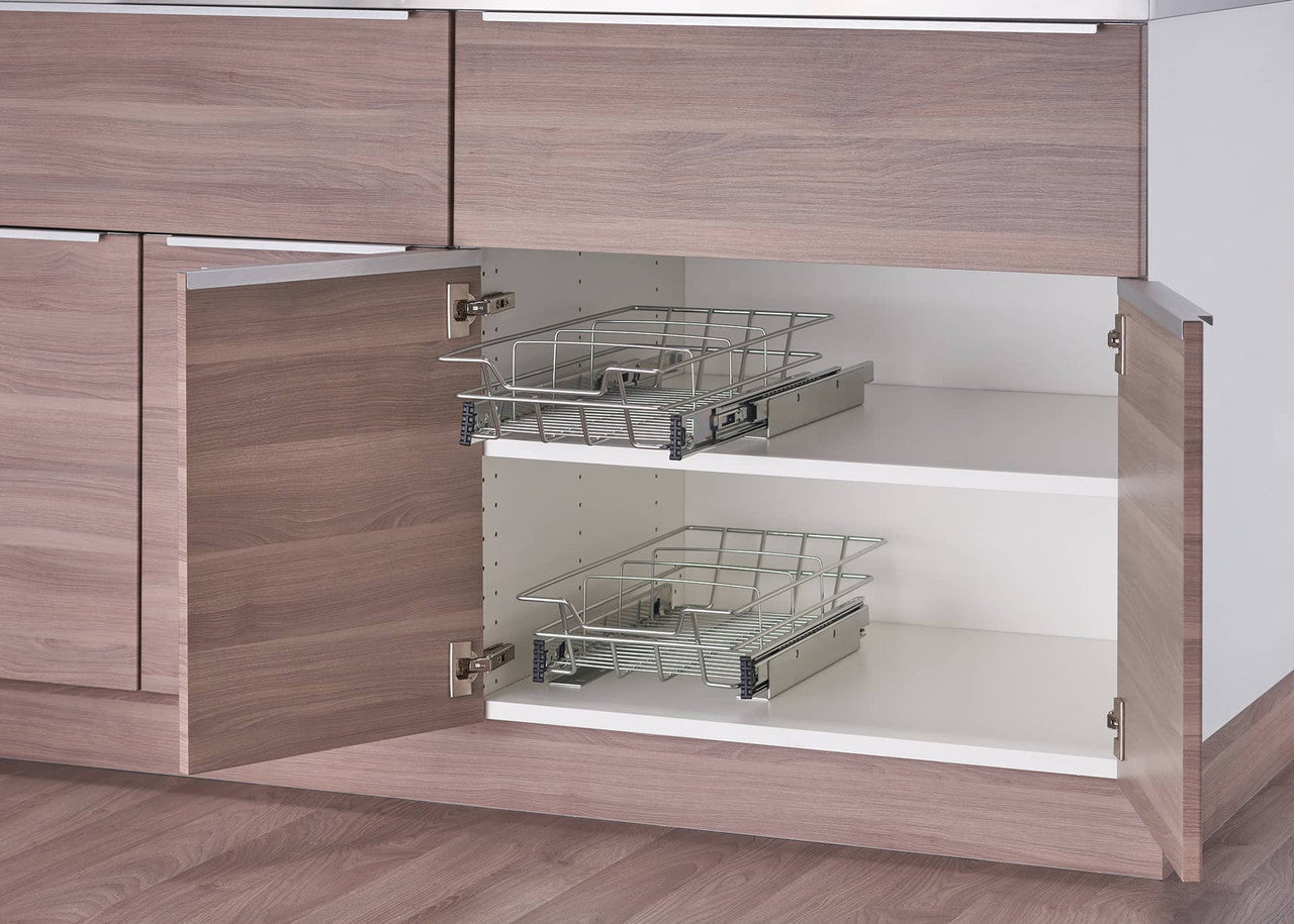 A close-up shows two chrome wire sliding drawers installed within a light brown and white cabinet. Each drawer is empty and extended slightly, revealing the smooth sliding mechanism attached to the cabinet walls.