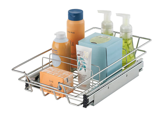 A chrome wire sliding drawer is shown extended, filled with various bathroom toiletries. The drawer contains a bar of soap in an orange box, a tube of lotion, a blue box of tissues, a bottle of orange foam soap, a tall orange bottle of body wash with a blue cap, and two clear pump bottles of green liquid soap.