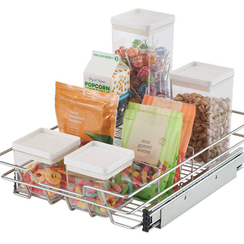 A chrome wire sliding drawer is pulled partially out, revealing various food items stored inside. The drawer contains clear plastic containers with white lids holding colorful candies, a bag of popcorn, bags of gummy candies, and a clear container filled with nuts.