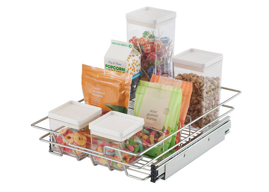 A chrome wire sliding drawer is pulled partially out, revealing various food items stored inside. The drawer contains clear plastic containers with white lids holding colorful candies, a bag of popcorn, bags of gummy candies, and a clear container filled with nuts.