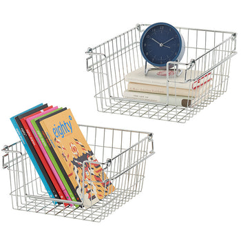 Two chrome wire baskets are shown on a white background. One basket contains a stack of books and a blue clock, while the other holds a stack of colorful books. The baskets are stackable and appear to be part of a storage solution.