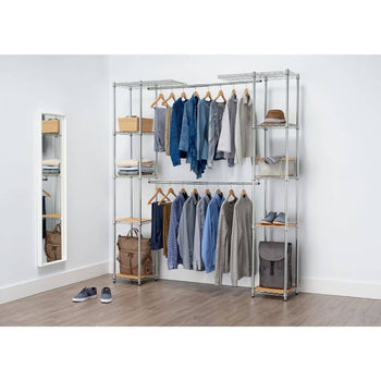 
An expanded chrome closet organizer with wooden shelves is filled with clothes, shoes, and accessories. It features hanging rods, multiple shelves, and various compartments for storage, with a full-length mirror leaning against the wall to the left.