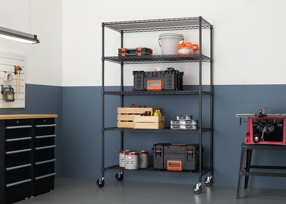 A five-tier, black wire shelving unit with wheels is filled with tools and supplies in a clean garage or workshop. The shelves hold various items including a large gray bucket, plastic storage cases, a wooden crate, and paint cans.