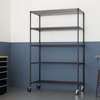 A tall, five-shelf wire shelving unit with locking wheels stands in the middle of a garage workshop. The shelves are empty and the unit is positioned in front of a two-toned wall, with the upper half painted white and the lower half a dark, dusty blue.