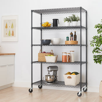 A tall, five-shelf wire rack on wheels stands in a modern kitchen. The shelves are organized with various kitchen items, including bowls, food ingredients, a stand mixer, and decor like a potted plant and a painting.