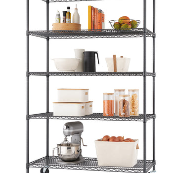 A wire shelving unit on wheels, with five shelves displaying various kitchen items. From top to bottom, the shelves hold a fruit bowl, books, pantry containers, and a stand mixer.