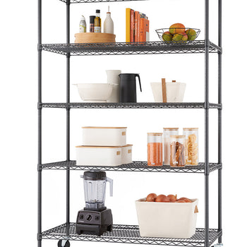 A black five-tier wire rolling shelf unit displays an array of organized kitchen items set against a plain white background. The shelves showcase oil bottles on a wooden turntable, cookbooks, a bowl of fresh fruit, storage containers, dry food jars, a countertop blender, and a fabric bin filled with onions.   