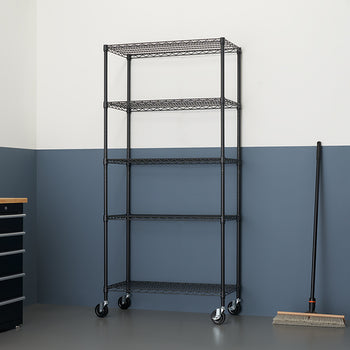 A tall, black, five-tier wire shelving unit with caster wheels stands against a wall painted white over dark blue-gray. To the right of the shelf, a broom rests against the wall.