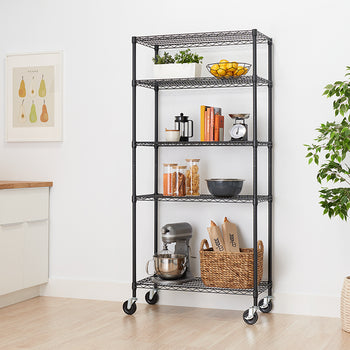 A five-tier black wire shelving unit with locking casters is shown, fully stocked with kitchen and home items. The shelves hold a stand mixer, a woven basket, glass storage containers, books, kitchen scales, and potted herbs and lemons.