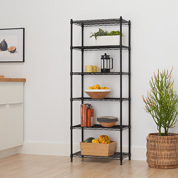 A six-tier, black wire shelving unit is pictured, filled with kitchen and decorative items in a bright, modern room. Items include potted plants, a coffee press, a bowl of lemons, books, and gourds in a wooden crate.
