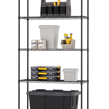 A black wire shelving unit stands against a white background, filled with various workshop and home organization supplies on each of its five shelves. On the bottom is a large black storage tote; above it are three stacked black and yellow tool boxes and a small white plastic container; on the middle shelf sits an open-top fabric tool organizer, three paint cans, and assorted spray cans.