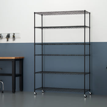 A black six-shelf wire shelving unit with wheels sits in a garage or workshop space. The background features a white and dark blue two-toned wall, a wooden workbench, a rolling metal stool, a tool rack, and a large gray trash can.