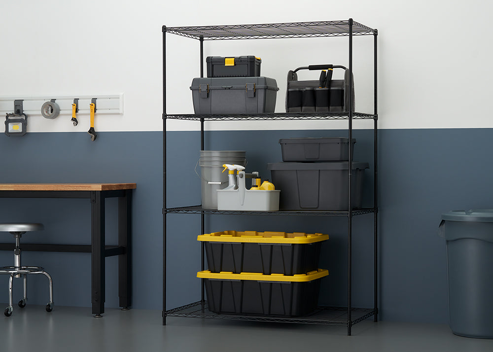 A black wire shelving unit stands against a two-toned wall (white above, dark blue below), organized with various gray and black storage containers and toolboxes. The shelves hold items like tool chests, a caddy with spray bottles, and two large black and yellow-lidded storage bins.
