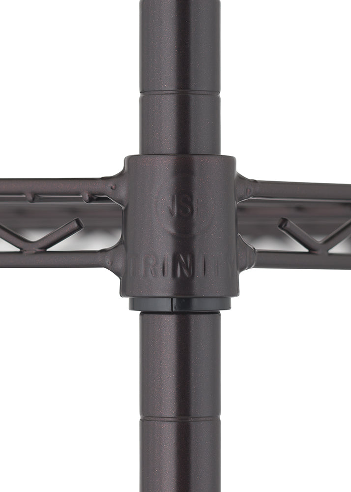 A close-up photograph focuses on the intersection of four posts and a wire shelf of a metal shelving unit. The center connector, which joins the vertical posts and horizontal shelves, is a dark bronze color and has the word "TRINITY" embossed on it.