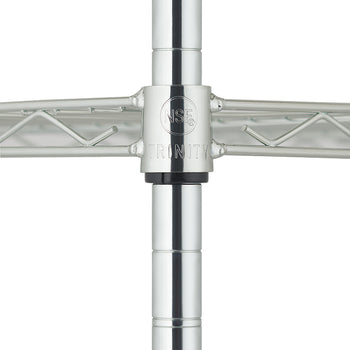 
A close-up, centered shot of a chrome wire shelving unit shows the joint where two horizontal shelves meet a vertical pole. The circular connection sleeve is engraved with the NSF certification mark and the brand name TRINITY.