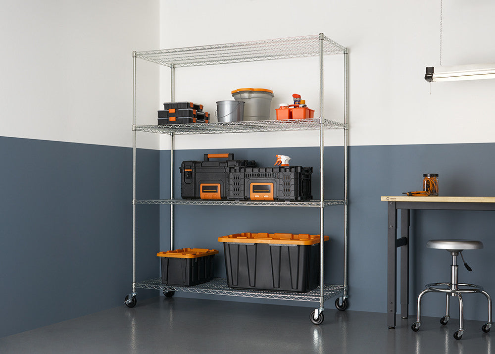 A 4-tier wire shelving unit with wheels is shown against a two-tone wall, holding various storage containers and tools. The shelving unit is made of silver metal and the background wall is half white and half dark blue.