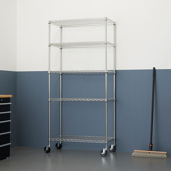A chrome wire shelving unit with five shelves on casters is centered in a room with a two-toned wall. The bottom half of the wall is dark gray, and the top half is white.