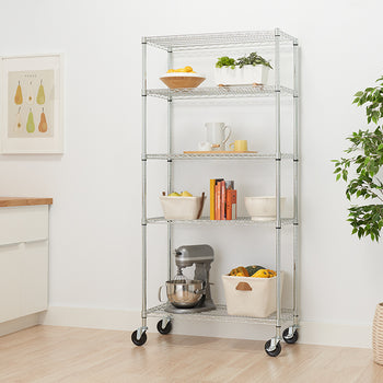 A five-tier wire shelving unit with wheels is filled with various items. The shelves hold a stand mixer, a large basket with gourds, books, bowls, and potted plants.