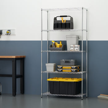 A tall, 5-tier chrome wire shelving unit is positioned against a wall in a workshop, fully stocked with storage bins, tool boxes, paint cans, and cleaning supplies. To the left, a portion of a workbench and a silver rolling stool are visible, along with wall-mounted tool storage.