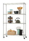 A four-tier chrome wire shelving unit on wheels is loaded with kitchen items. The shelves hold containers of dry goods, a spice rack, a kettle, cooking utensils, a popcorn maker, and a wooden crate with squash.