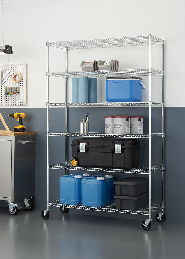 A six-tier chrome wire shelving unit on caster wheels, positioned against a half-painted blue and white wall in a garage or workshop environment. The shelves are stocked with various utility items, including large blue plastic jugs, a wheeled black toolbox, paint cans, a blue cooler, and workshop paper towels.