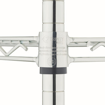 A close-up shot of the corner collar joint of a chrome wire shelf, showing where it connects to a vertical supporting post over a black plastic slip sleeve. The metal collar is stamped with the "TRINITY PRO" logo, an NSF certification mark, and text detailing weight capacities for evenly distributed loads.
