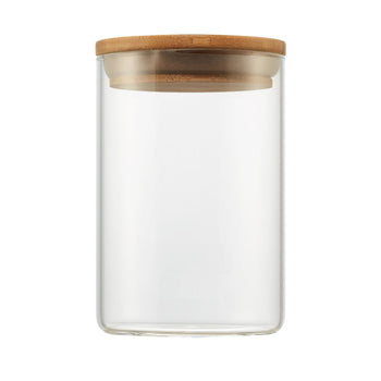 A clear glass medium canister with a cylindrical shape is shown. It is topped with a round, light brown wooden lid.